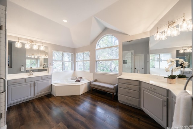 bathroom with wood-type flooring, shower with separate bathtub, vaulted ceiling, and vanity