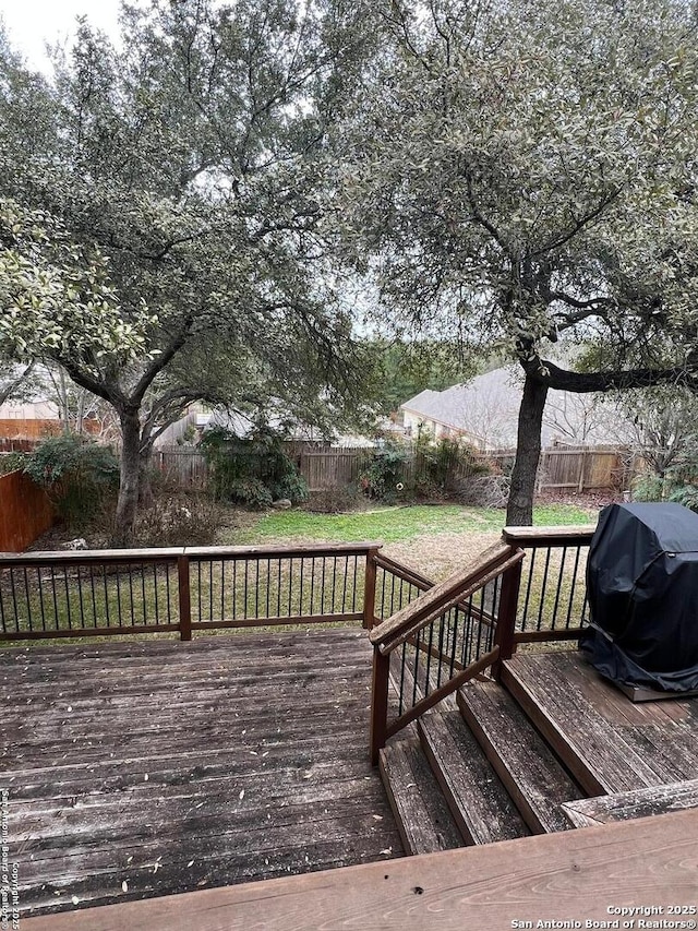 wooden terrace featuring area for grilling and a yard