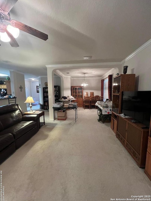 living room featuring ornamental molding, ceiling fan with notable chandelier, light colored carpet, and a textured ceiling