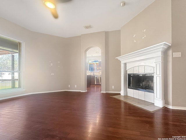 unfurnished living room featuring dark wood-type flooring and a tiled fireplace