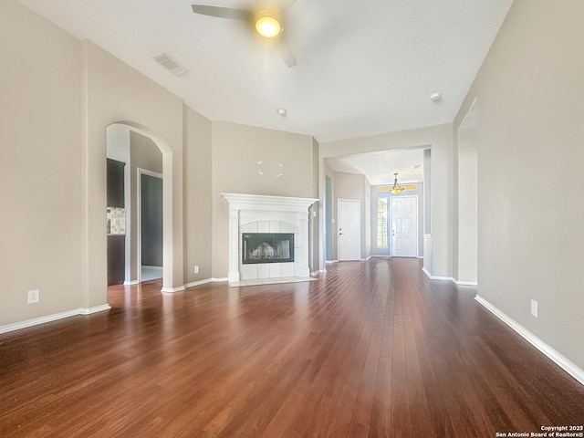 unfurnished living room with dark wood-type flooring, ceiling fan, and a fireplace