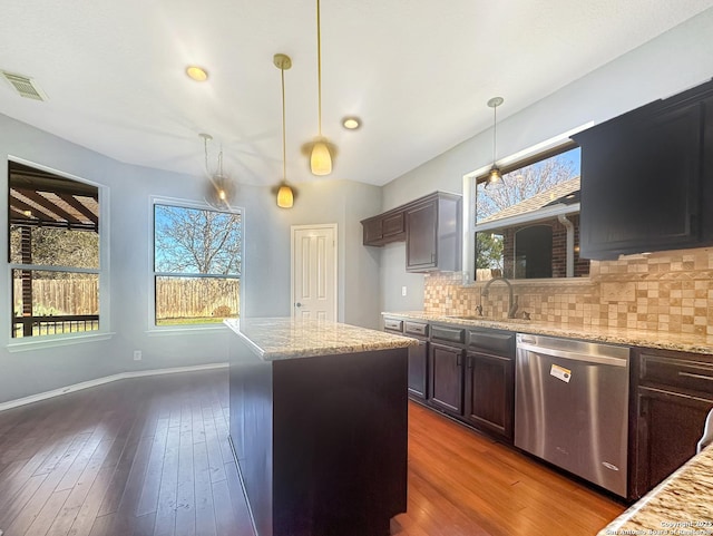 kitchen with sink, a center island, hanging light fixtures, dishwasher, and light stone countertops