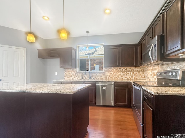 kitchen with stainless steel appliances, light stone countertops, hanging light fixtures, and sink