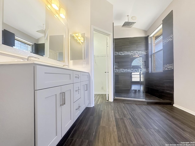 bathroom featuring hardwood / wood-style flooring, vanity, vaulted ceiling, and a shower