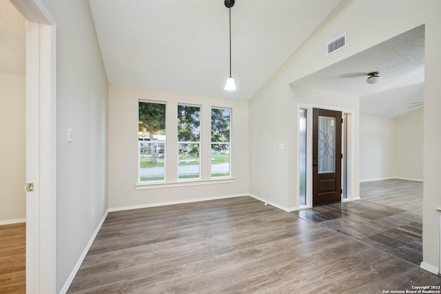 entryway with vaulted ceiling, dark wood-type flooring, and a textured ceiling