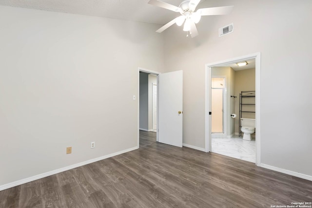 unfurnished bedroom featuring ensuite bathroom, dark wood-type flooring, and ceiling fan