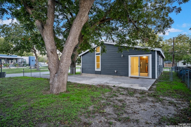 rear view of house featuring a lawn and a patio