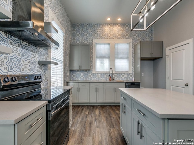 kitchen featuring dark wood-type flooring, black electric range oven, sink, gray cabinetry, and island range hood