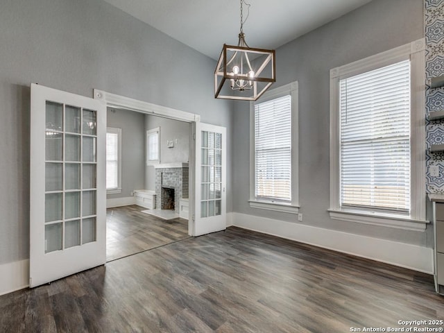 unfurnished living room featuring a wealth of natural light, dark hardwood / wood-style floors, and a chandelier