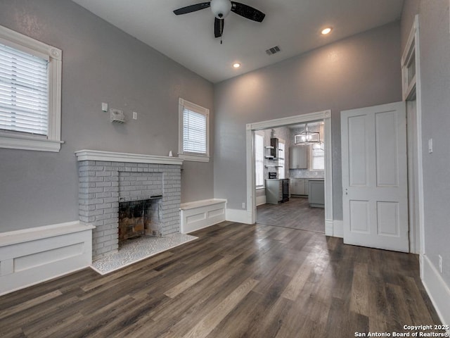 unfurnished living room featuring ceiling fan, dark hardwood / wood-style floors, and a brick fireplace