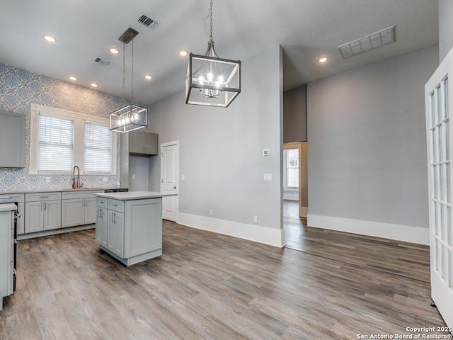 kitchen featuring pendant lighting, sink, gray cabinetry, hardwood / wood-style floors, and a center island