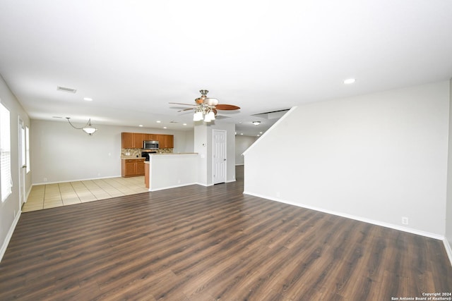 unfurnished living room with ceiling fan and dark hardwood / wood-style flooring