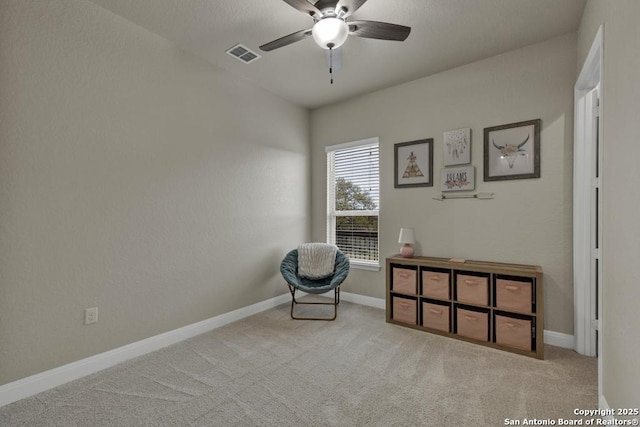 living area featuring light colored carpet and ceiling fan