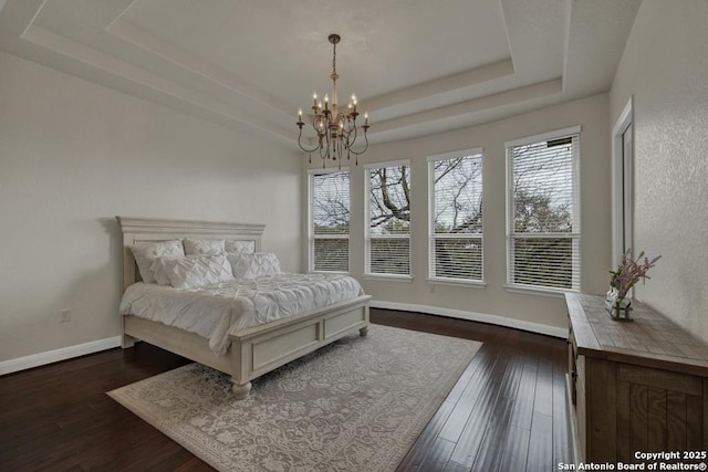 bedroom featuring dark wood-type flooring, a chandelier, and a tray ceiling