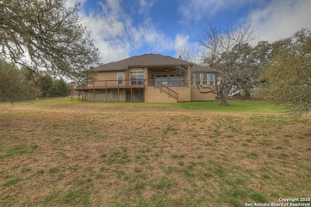 back of property with a wooden deck and a lawn