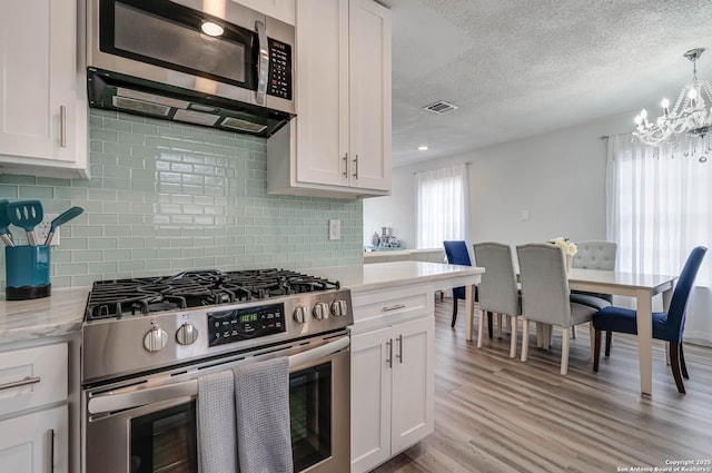 kitchen featuring appliances with stainless steel finishes, plenty of natural light, white cabinets, and light hardwood / wood-style flooring