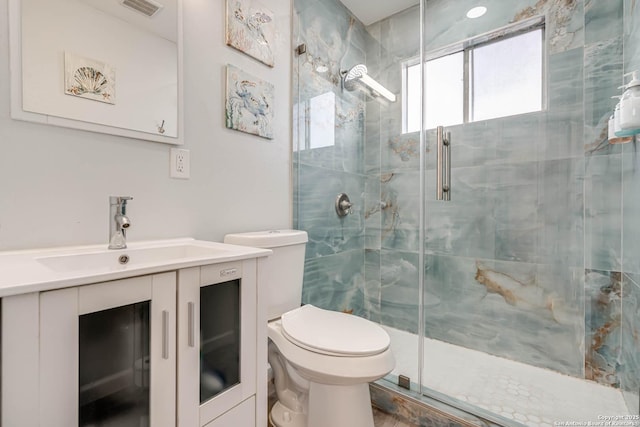 bathroom with vanity, a shower with door, and toilet