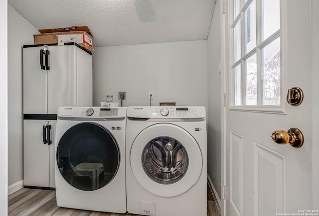 laundry area with washer and clothes dryer, cabinets, a textured ceiling, and light wood-type flooring