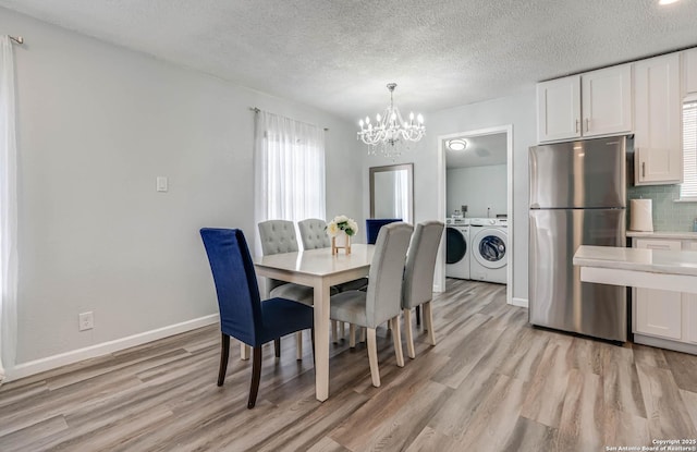 dining area featuring separate washer and dryer, light hardwood / wood-style floors, a textured ceiling, and a notable chandelier