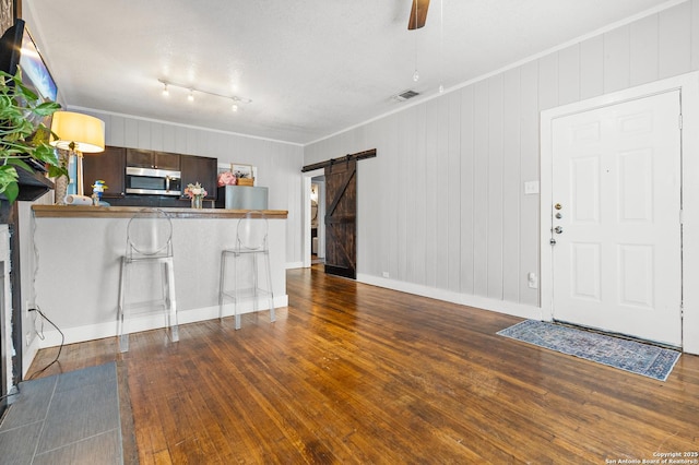 kitchen with dark wood-type flooring, a breakfast bar area, stainless steel appliances, kitchen peninsula, and a barn door