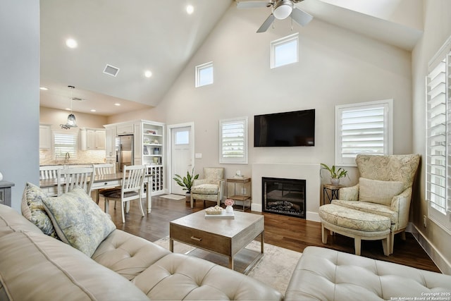 living room with high vaulted ceiling, ceiling fan, and light wood-type flooring