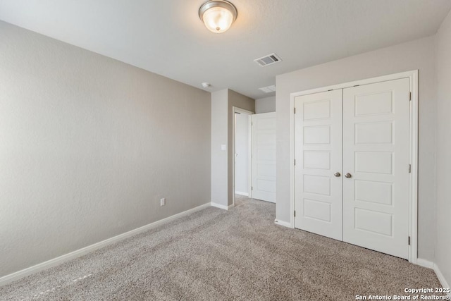 unfurnished bedroom with light colored carpet and a closet