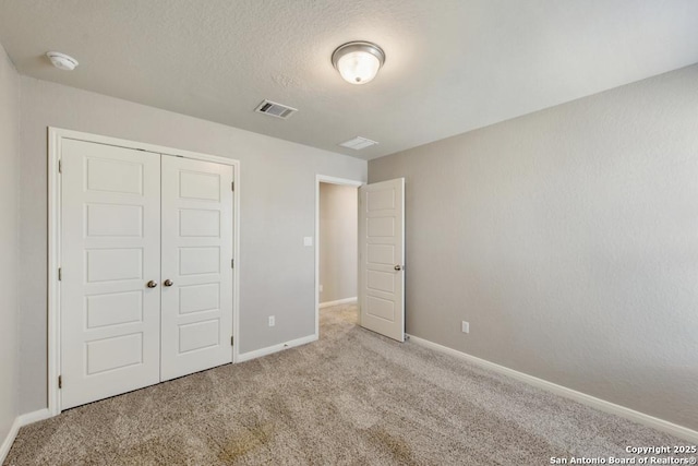 unfurnished bedroom featuring light colored carpet, a closet, and a textured ceiling