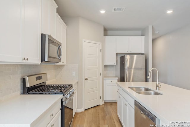 kitchen featuring white cabinetry, sink, light hardwood / wood-style floors, and appliances with stainless steel finishes