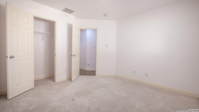 unfurnished bedroom with light carpet and a closet