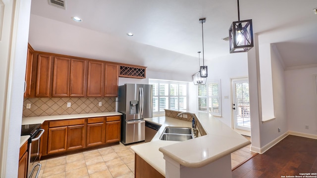 kitchen with sink, hanging light fixtures, a kitchen island, stainless steel appliances, and backsplash