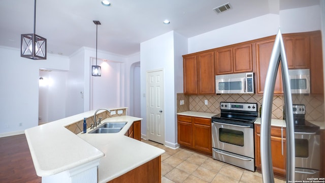 kitchen with an island with sink, stainless steel appliances, sink, and hanging light fixtures