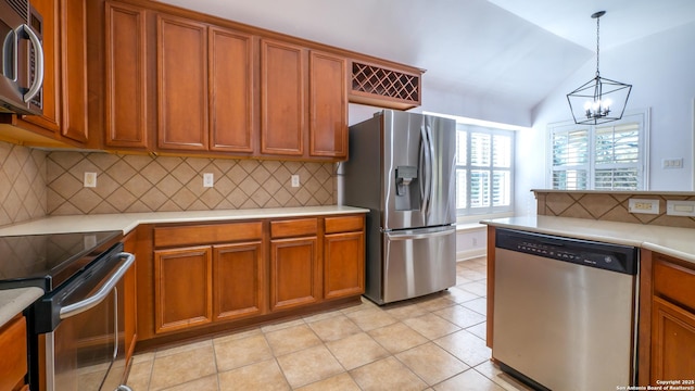 kitchen featuring hanging light fixtures, stainless steel appliances, tasteful backsplash, light tile patterned flooring, and vaulted ceiling