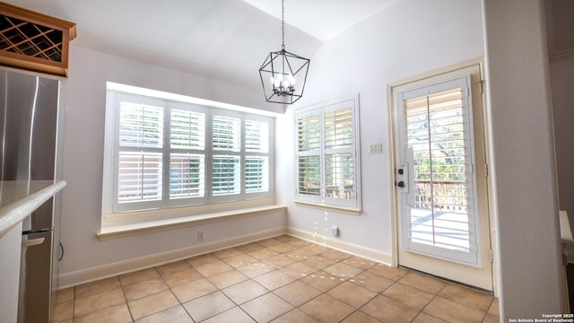 unfurnished dining area featuring light tile patterned flooring, lofted ceiling, and a notable chandelier