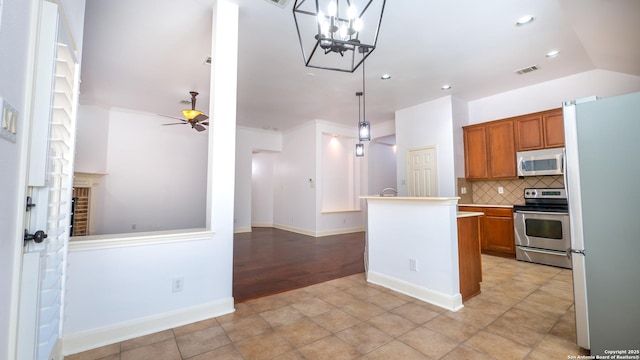 kitchen featuring lofted ceiling, backsplash, hanging light fixtures, ceiling fan, and stainless steel appliances