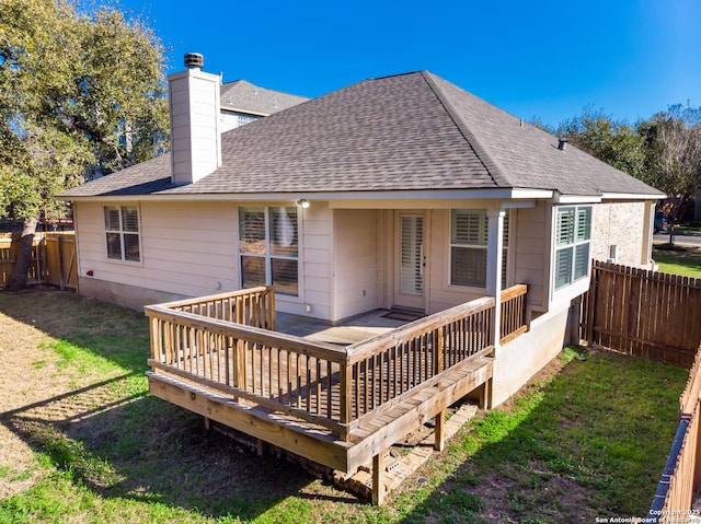 rear view of house with a wooden deck and a lawn