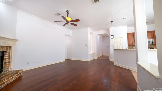 unfurnished living room with dark hardwood / wood-style floors, ceiling fan, a fireplace, and crown molding