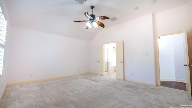 interior space with ceiling fan, ensuite bath, lofted ceiling, and light carpet