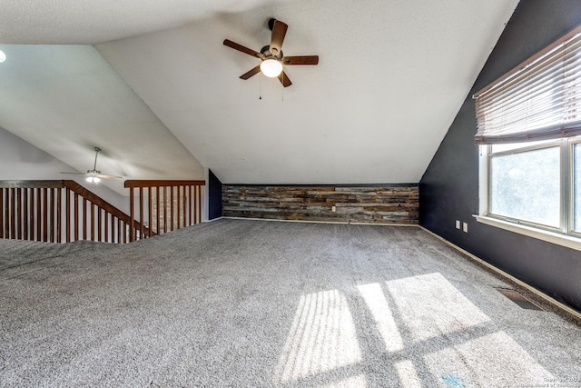 bonus room featuring lofted ceiling, carpet, ceiling fan, and wood walls