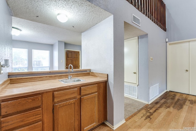 kitchen with light hardwood / wood-style floors, sink, and a textured ceiling