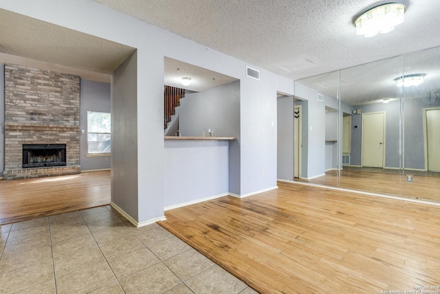 empty room featuring hardwood / wood-style flooring, a brick fireplace, and a textured ceiling