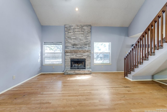 unfurnished living room with vaulted ceiling, light hardwood / wood-style floors, and a brick fireplace