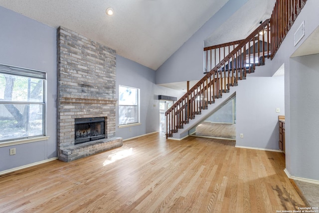 unfurnished living room featuring a fireplace, high vaulted ceiling, and light hardwood / wood-style flooring