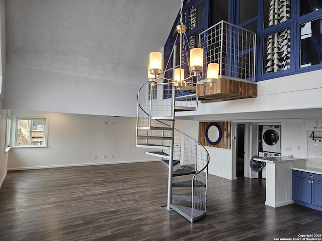 stairs featuring stacked washer and dryer, a high ceiling, hardwood / wood-style floors, and a textured ceiling