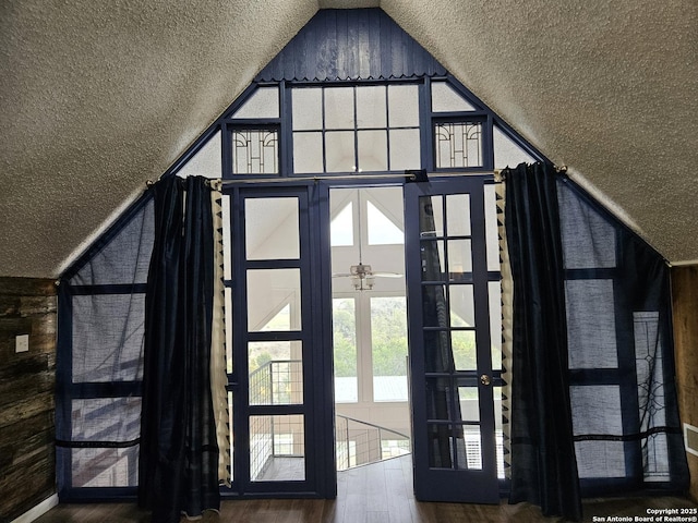 doorway with lofted ceiling, hardwood / wood-style floors, french doors, and a textured ceiling