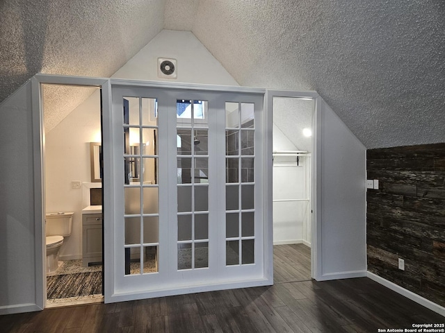 additional living space featuring lofted ceiling, dark hardwood / wood-style floors, and a textured ceiling