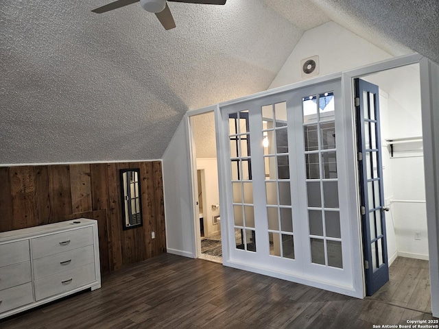 bonus room with dark wood-type flooring, ceiling fan, a textured ceiling, vaulted ceiling, and wood walls