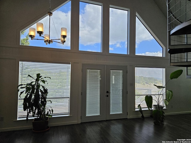 doorway to outside with a towering ceiling, dark wood-type flooring, a chandelier, and french doors