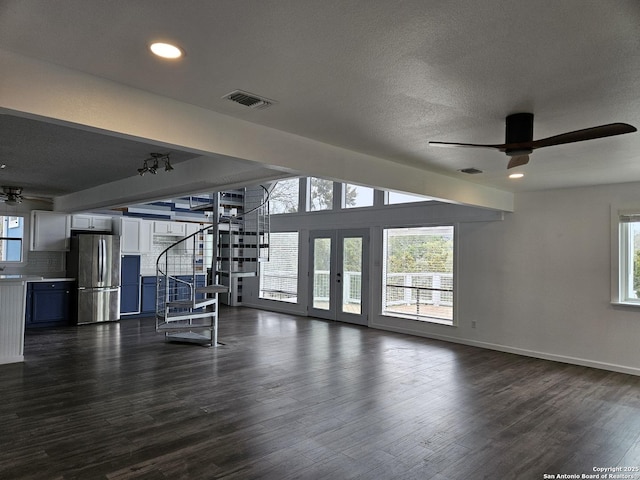 unfurnished living room featuring dark hardwood / wood-style flooring, a textured ceiling, and ceiling fan