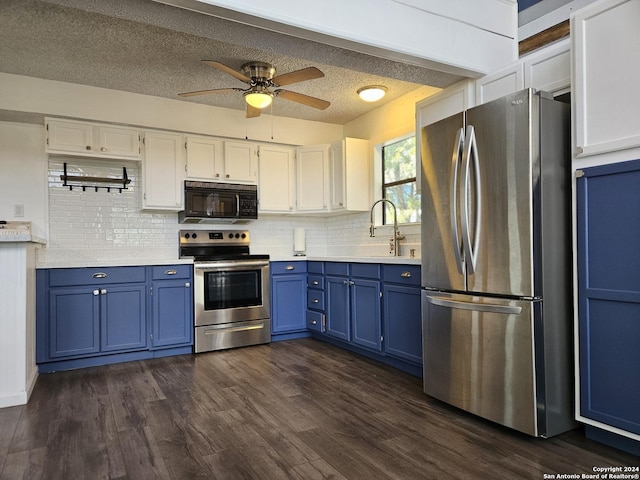 kitchen featuring dark wood-type flooring, appliances with stainless steel finishes, white cabinetry, blue cabinets, and decorative backsplash