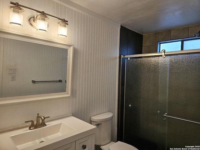 bathroom with a shower with door, vanity, and toilet